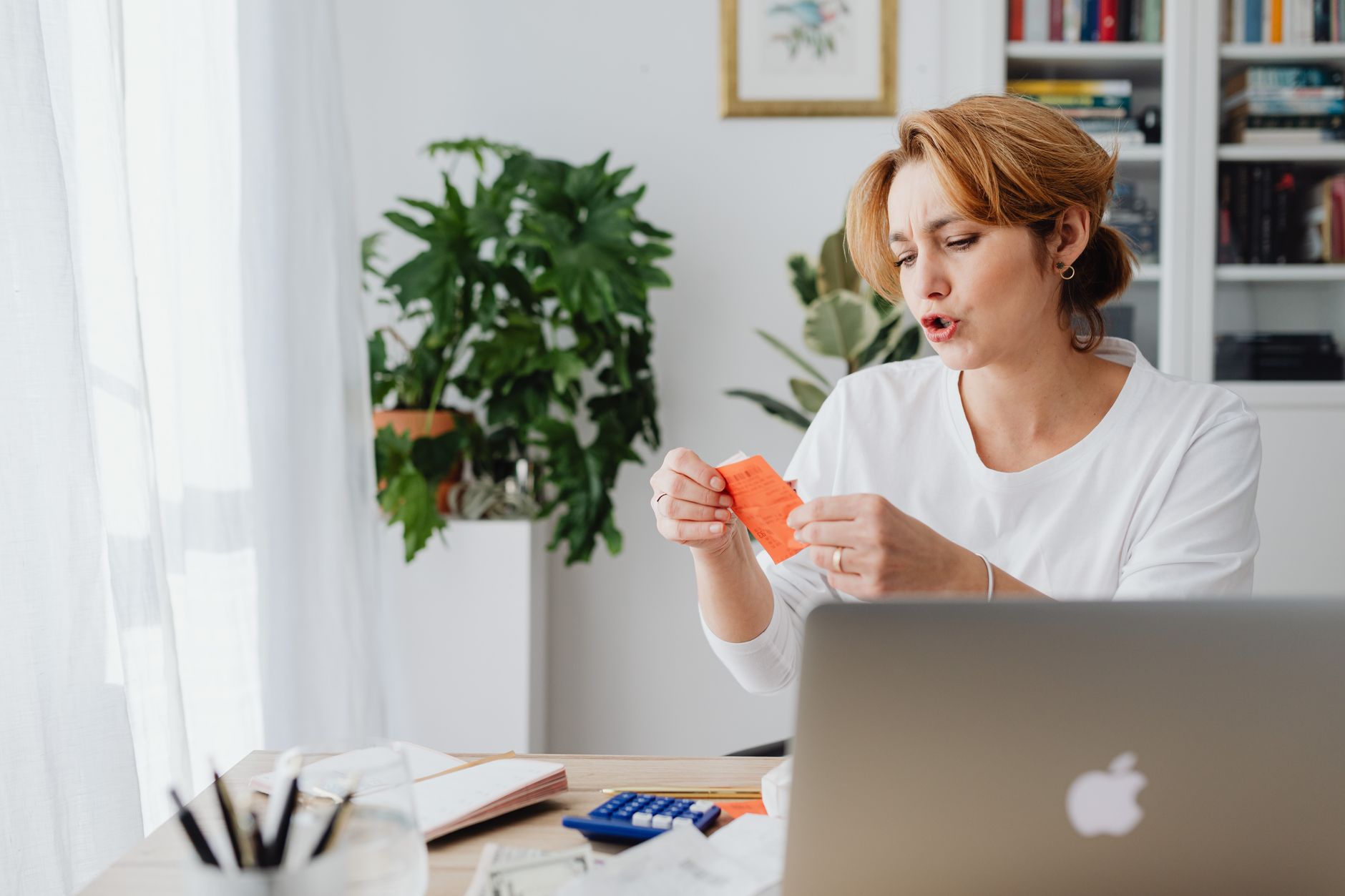 明るい部屋で電気代の明細をチェックして高さに驚く女性