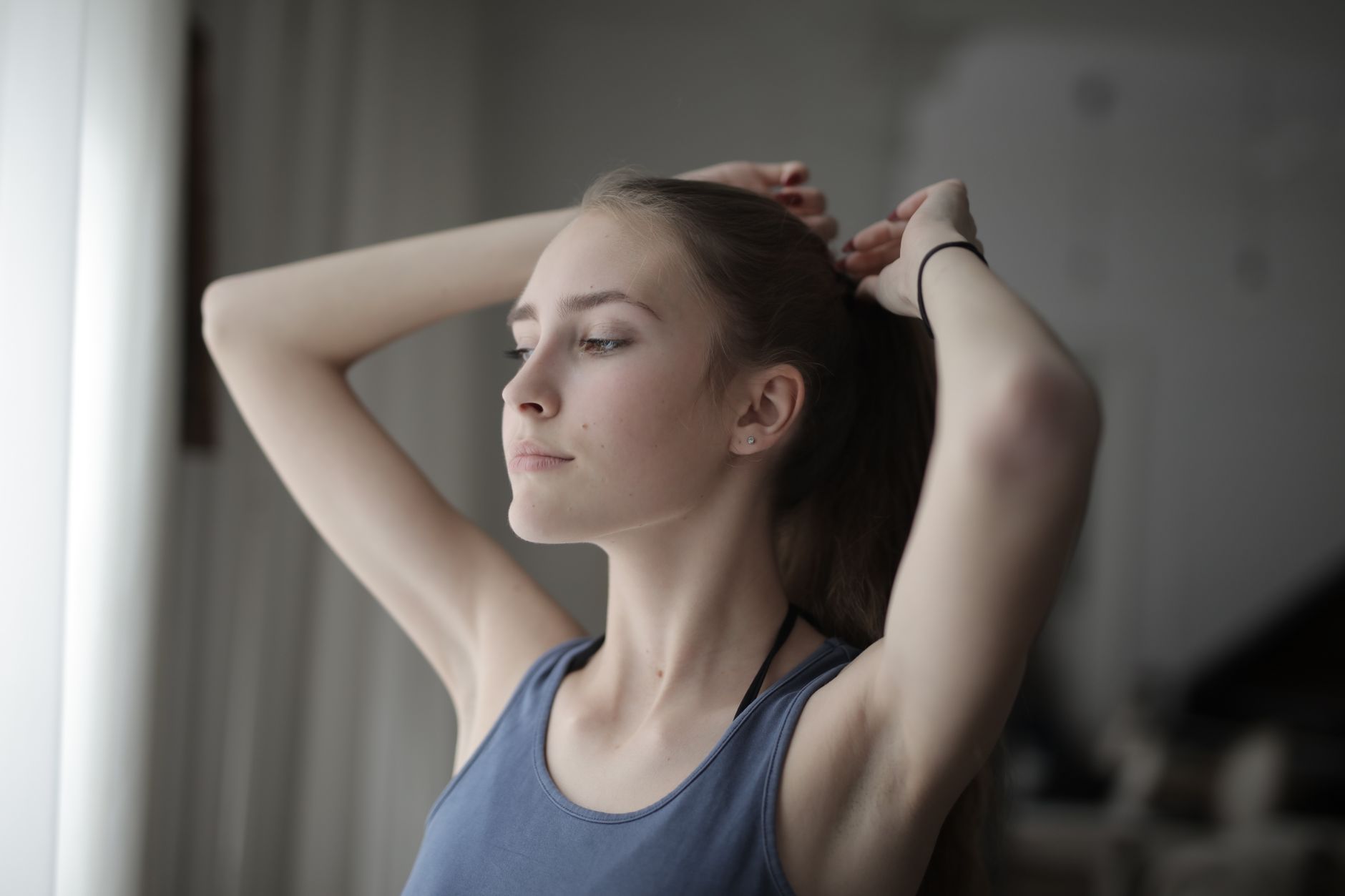 襟足の髪をまとめる女性(首掛け扇風機の髪の巻き込みを防ぐ装着前の準備イメージ)