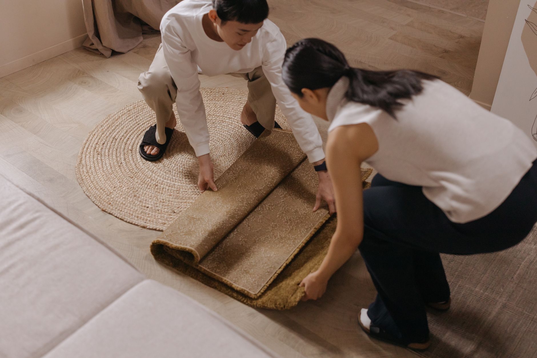 二人でラグを床に広げているところ