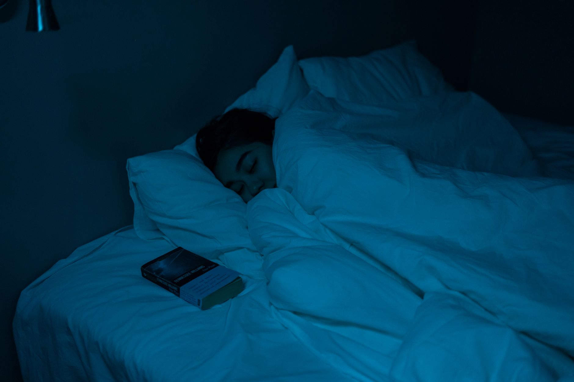 夜の寝室でサーキュレーターをつけっぱなしにして眠る様子