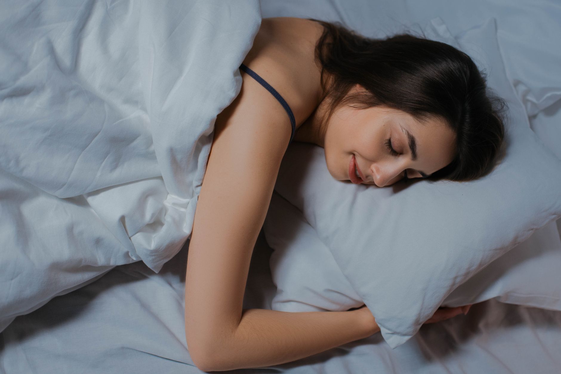 白い寝具のベッドで眠る人