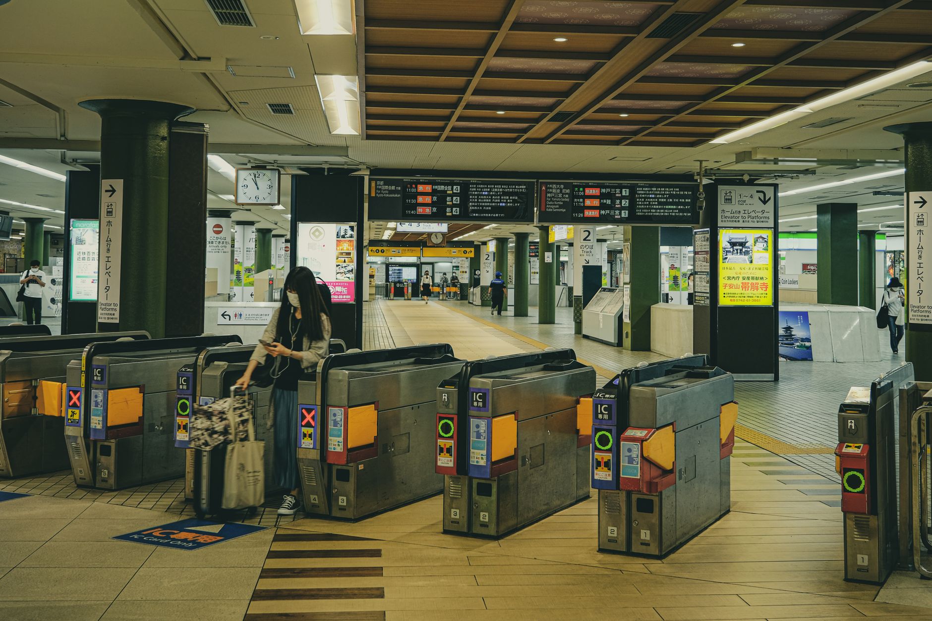 ICカード専用と表示された自動改札機が並ぶ駅の構内。荷物を持った人が通ろうとしている。