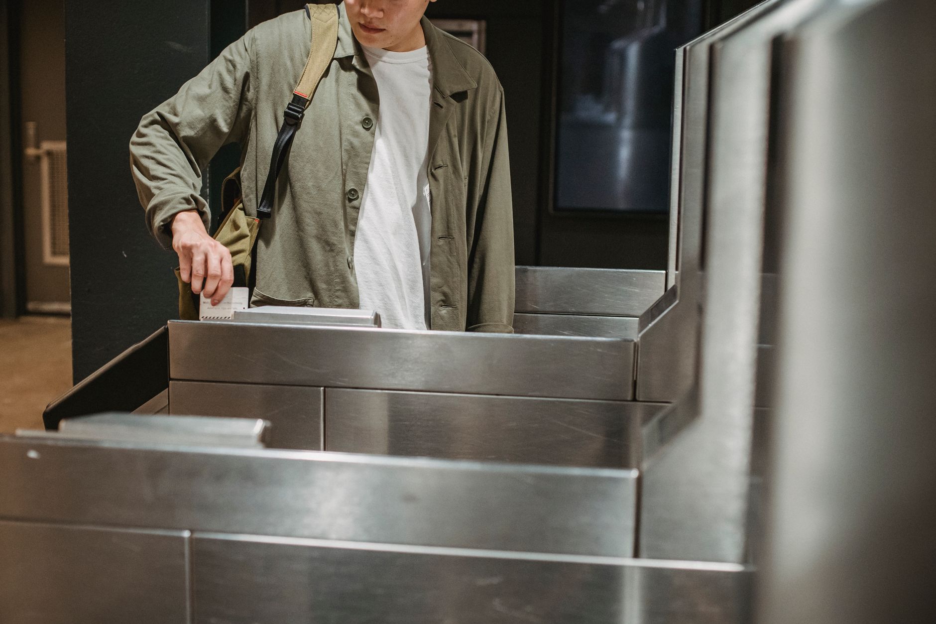 駅の自動改札機に切符を差し入れて、通り抜けようとしている人の手元。